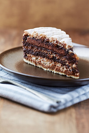 Piece of chocolate cake on a plate on wooden background. Selective focus.
