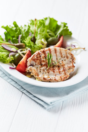 Grilled meat with fresh vegetable salad on white wooden background.の写真素材