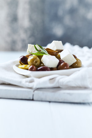 Greek olives with feta cheese and olive oil on a white plateの写真素材