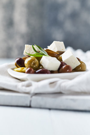 Green and black olives with feta cheese on white plate.の写真素材