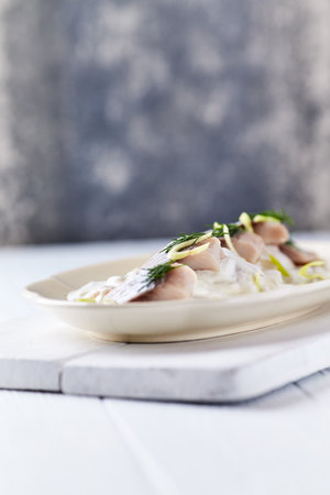 Marinated herring fillets with dill on a white plateの写真素材