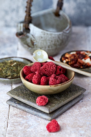 Dried raspberries in a ceramic bowl on a stone backgroundの写真素材
