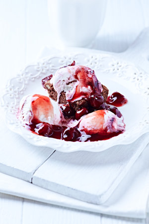 Chocolate cake with strawberry sauce and ice cream on a white wooden backgroundの写真素材