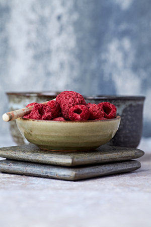 Dried raspberries in a ceramic bowl on a wooden backgroundの写真素材
