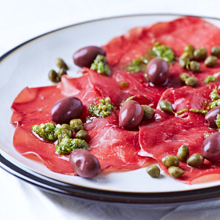 Slices of beef carpaccio with olives and capers. Close-up.の写真素材
