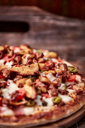 Pizza with meat and vegetables on a wooden background. Selective focus.の写真素材