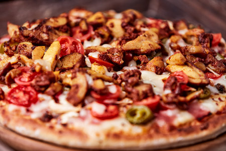 Pizza with meat, vegetables and cheese on a wooden background.の写真素材