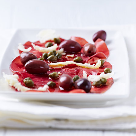 Italian prosciutto carpaccio with olives and capersの写真素材