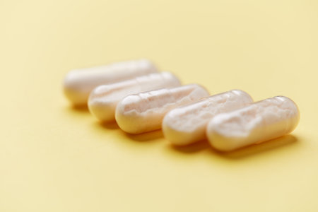 Close-up of white pills on yellow background. Focus on foreground.