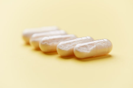 Capsules of white pills on yellow background. Focus on foreground, soft bokeh.の写真素材