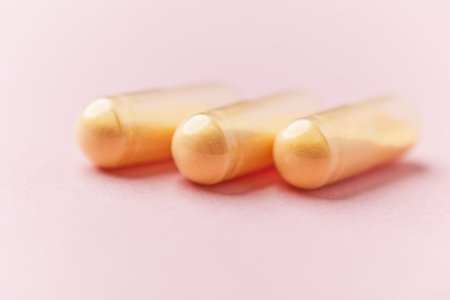 Close-up of two golden capsules on pink background with copy spaceの写真素材