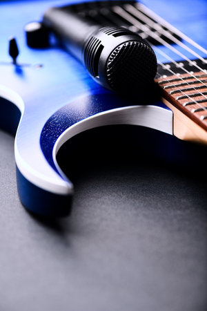 Blue acoustic guitar and microphone on a black background. Music concept.
