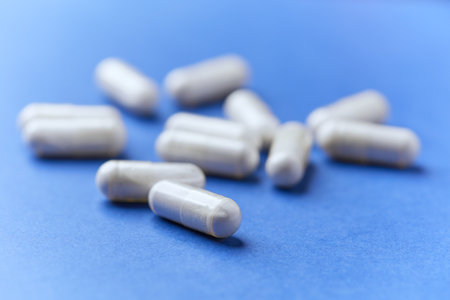 White capsules on blue background. Focus on foreground, soft bokeh.