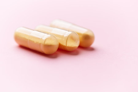 Capsules of golden color on a pink background close-upの写真素材