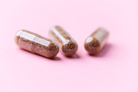 Capsules of pills on a pink background. Selective focus.