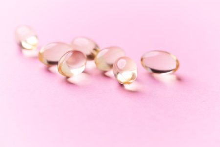 Cod liver oil omega 3 gel capsules on pink pastel background.