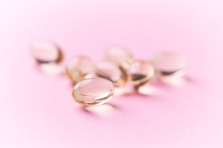Close up of Omega 3 fish oil capsules on pink background with copy space