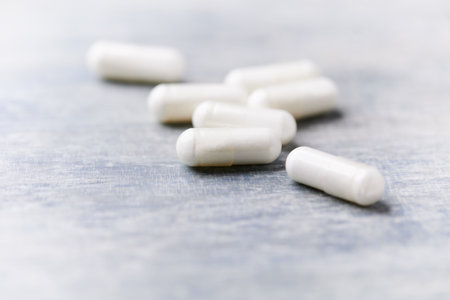 White pills on a blue wooden table. Focus on foreground, shallow DOF.の写真素材