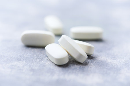 White pills on a gray background. Focus on foreground, shallow depth of field.