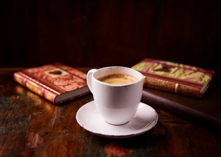 Coffee cup and old books on wooden table in dark roomの写真素材