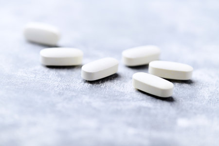 White pills on a gray background. Focus on foreground, shallow DOF.