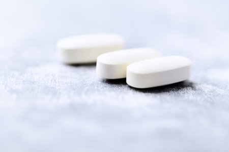 White pills on a gray background. Focus on foreground, shallow depth of field.