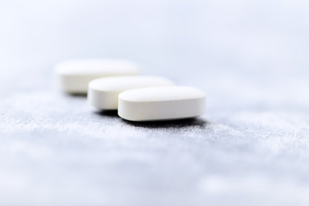 White pills on a gray background. Focus on foreground, shallow depth of field.の写真素材