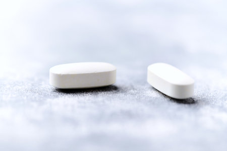 Two white pills on gray background. Focus on foreground, shallow DOF.の写真素材