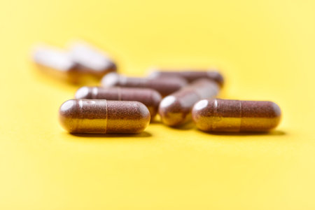 Close up of capsule pills on yellow background. Focus on foreground, soft bokeh.