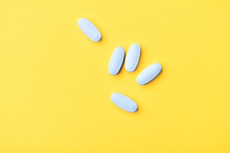 Blue pills on yellow background. Flat lay, top view, copy spaceの写真素材