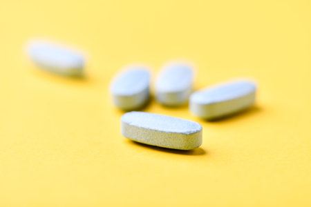 Pills on a yellow background. Focus on foreground, soft bokeh.の写真素材
