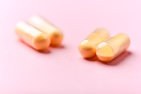 Two golden pills on pink background. Focus on foreground, shallow DOF.の写真素材