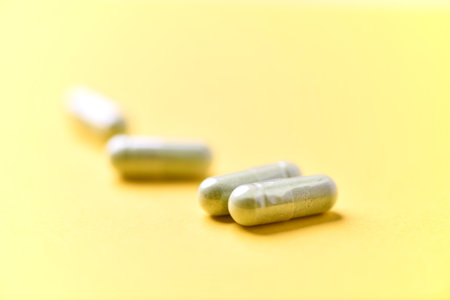Green capsules on yellow background. Focus on foreground, soft bokeh.
