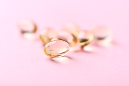 Cod liver oil omega 3 gel capsules on pink background, close upの写真素材