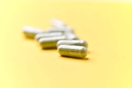 Close up of capsules on yellow background. Focus on foreground, soft bokeh.の写真素材