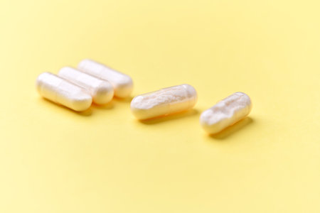 Close up of white pills on yellow background. Focus on foreground.の写真素材