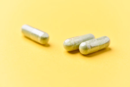 Close-up of two green capsules on yellow background with copy spaceの写真素材
