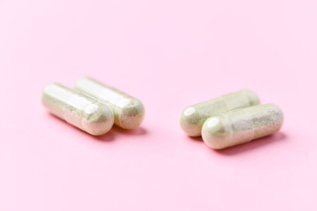 Close up of green capsule pills on pink background with copy space.の写真素材