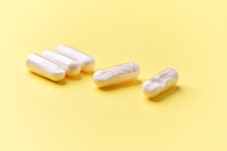 White pills on yellow background. Focus on foreground, soft bokeh.の写真素材