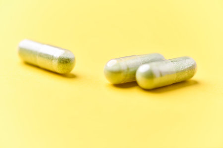 Two capsules on yellow background. Focus on foreground, soft bokeh.の写真素材