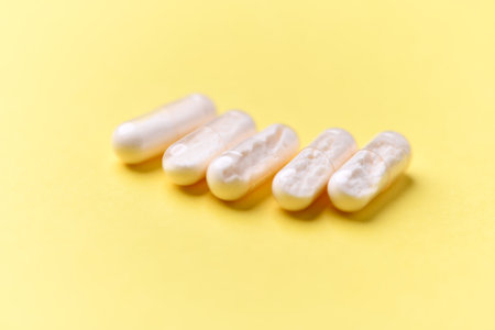 White pills on yellow background. Focus on foreground, soft bokeh.
