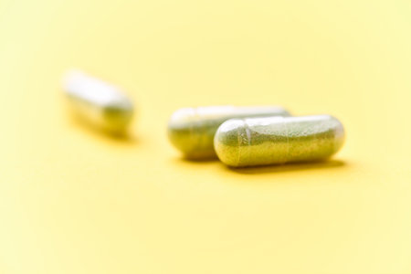 Green capsules on yellow background. Focus on foreground, soft bokeh.の写真素材