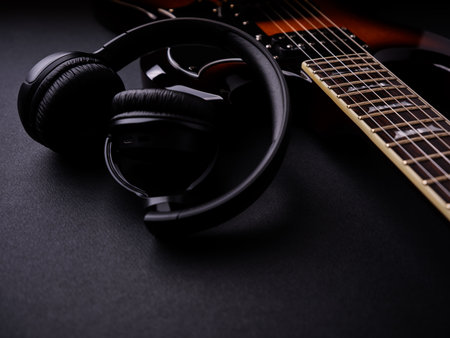 Headphones and electric guitar on a black background. Music concept.の写真素材