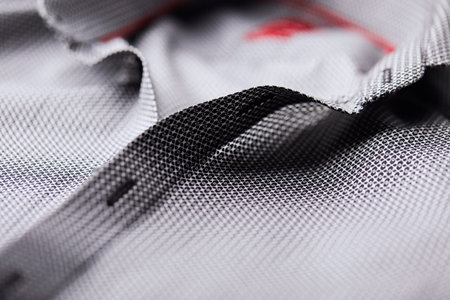 Close up of a gray sports shirt with a black and white stitching