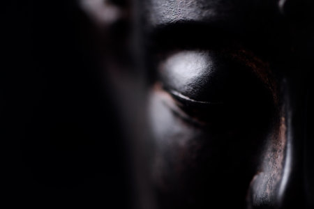 Close up of the face of a buddha on a black backgroundの写真素材