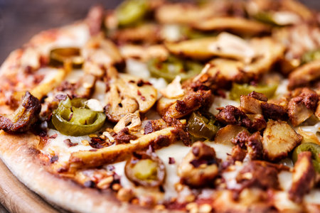 pizza with meat, mushrooms and olives on a wooden tableの写真素材