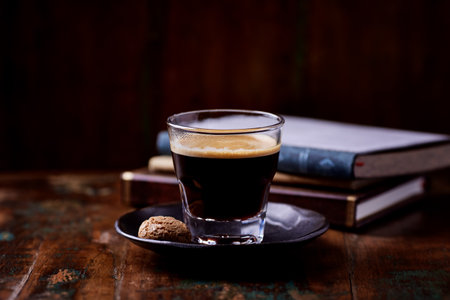 Cup of coffee with cookies and books on dark wooden background.の写真素材