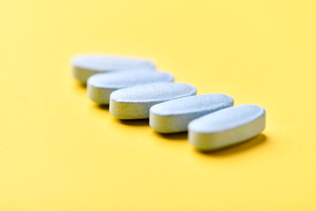 Pills isolated on yellow background. Focus on foreground, soft bokeh.