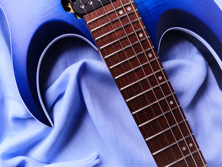 Blue acoustic guitar on a blue fabric background. Close up.
