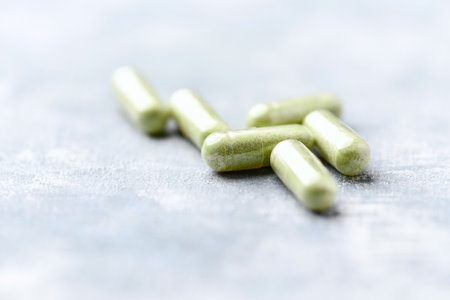 Green pills on a light blue background. Focus on foreground, shallow depth of field.